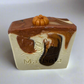Bar of soap with brown and beige swirls and a small pumpkin on top, branded 'Marbela'.
